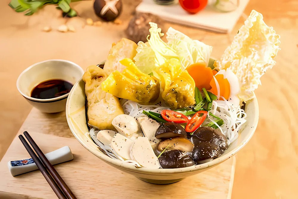 Vegan Hu Tieu includes sweet broth, mushrooms, tofu, and wontons, paired with chilli soy sauce, creating a spicy yet satisfying flavor 
